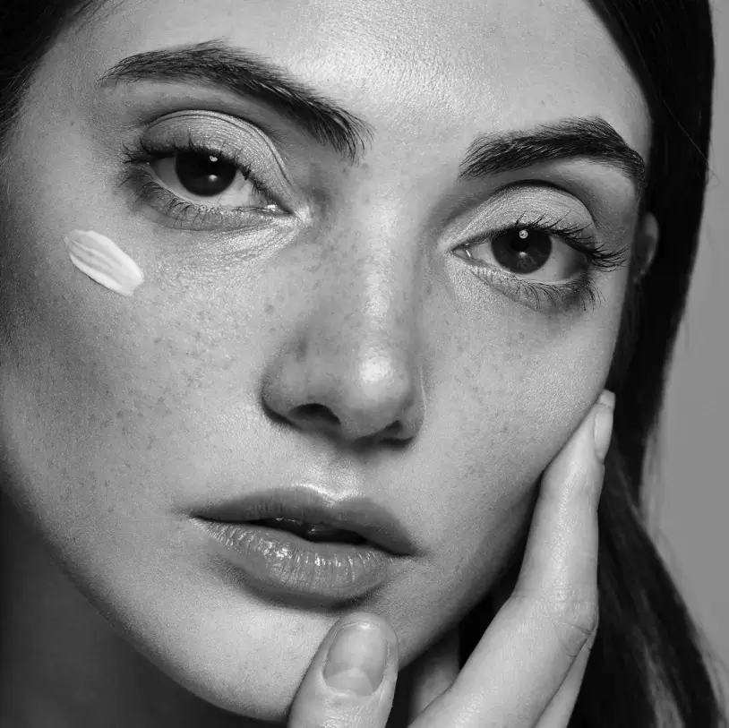 QMS Active Glow ILLUMIntense Serum Model mit aufgetragenen Serum im Gesicht